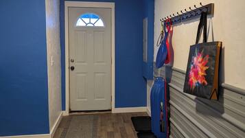 A hallway with blue walls, a white door, and a coat rack with a bicycle and a painting.