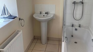 A bathroom with a sink, mirror, shower, and radiator. - Swallow Bach, Couples Bolt Hole (Llangefni)