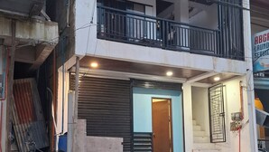 Un edificio de dos pisos con un balcón, una tienda cerrada y una motocicleta estacionada.