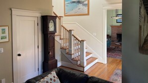 A staircase with a wooden handrail and white balusters, leading to a living area with a black leather couch and a large painting of a beach scene above the stairs. - Lovely 4-bedroom house in  charming Coronado, "The Golden Triangle" (Coronado)