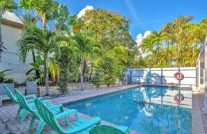 A swimming pool with a clear blue water surface, surrounded by palm trees and a white fence. - Later, Gator - Pool - Canal - Wilton Drive (Oakland Park)