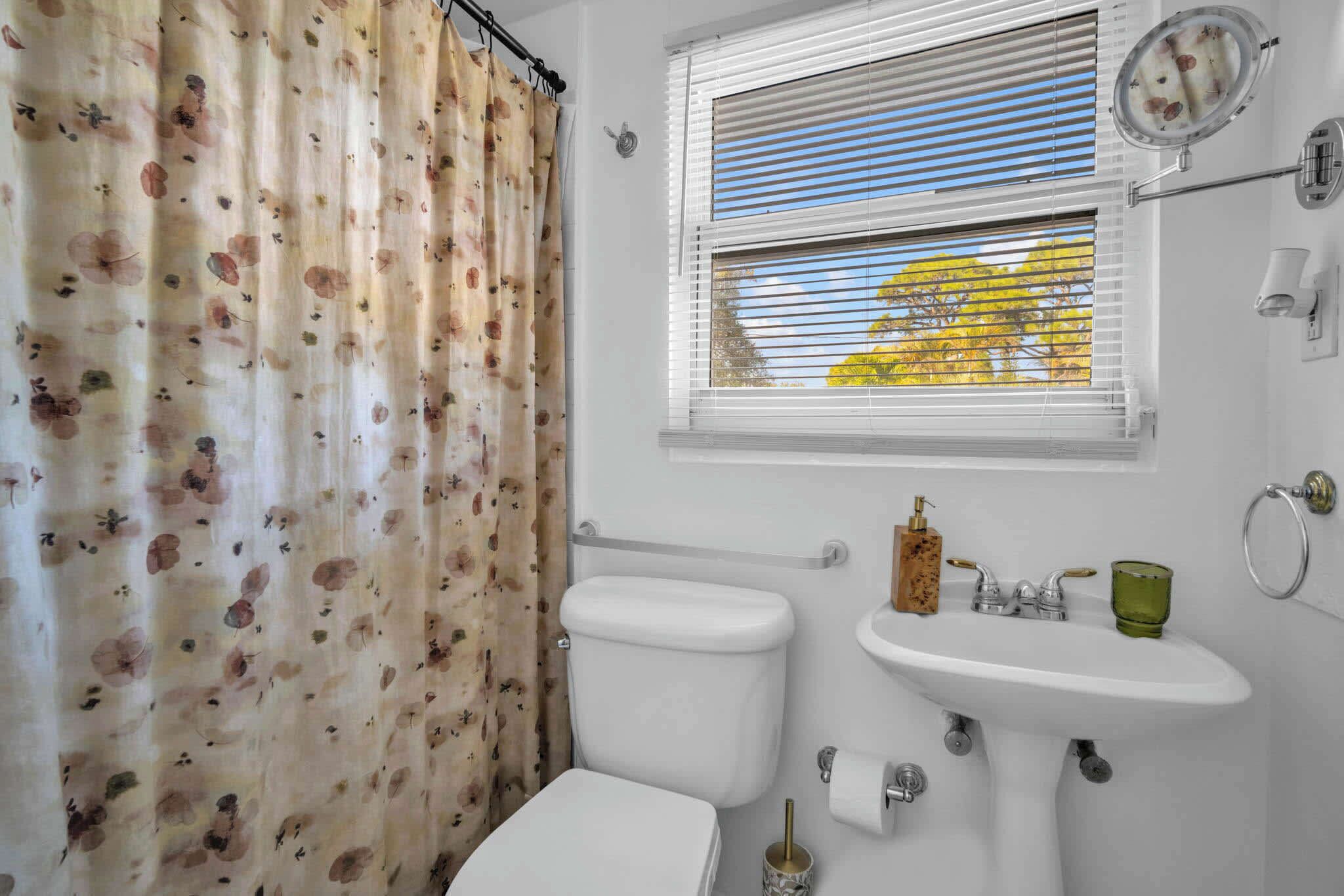 A bathroom with a toilet, sink, and window with blinds.