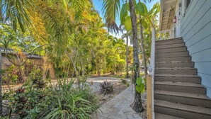 Un escalier en bois menant à une maison avec un chemin qui traverse le jardin.