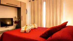 A hotel room with a bed, a TV, and towels on the bed. - ANTONIO APARTMENT IN ROME (Roma)