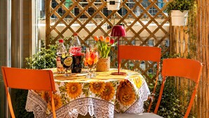 A table set with a floral tablecloth, two chairs, a bottle of Coca-Cola, a bottle of Schweppes, a glass of orange juice, and a red lamp. - ANTONIO APARTMENT IN ROME (Roma)