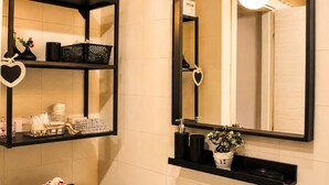 A bathroom with a black shelf holding toiletries, a heart-shaped decoration, and a mirror with a sign above it. - ANTONIO APARTMENT IN ROME (Roma)