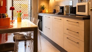 A modern kitchen with a dining area, featuring cabinets, a microwave, and a table with chairs. - ANTONIO APARTMENT IN ROME (Roma)