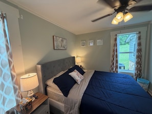 Une chambre à coucher avec un lit, des lampes de chevet, un ventilateur de plafond et une fenêtre avec des rideaux.