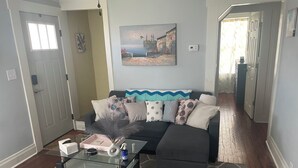 A living room with a dark-colored sofa, a glass coffee table, and a patterned rug. - Cozy 2-bedroom house in beautiful Andrews,NC with theater room and air hockey. (Andrews)