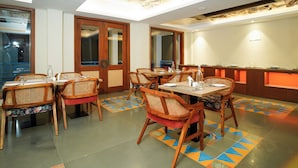 A dining area with wooden chairs and tables, a buffet counter, and a skylight ceiling. - Sukama Resort & Spa (Dhari)