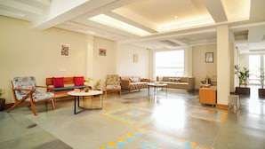 A spacious living area with a high ceiling, multiple seating arrangements, and a patterned floor. - Sukama Resort & Spa (Dhari)