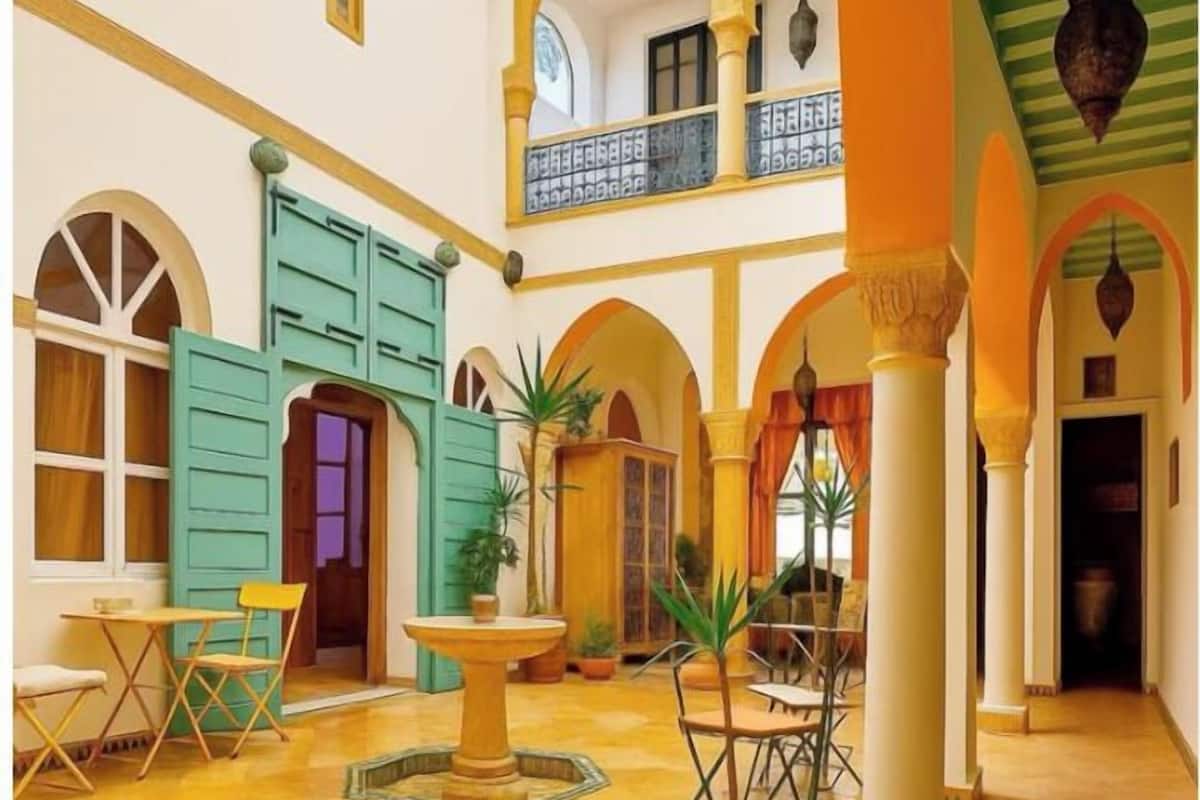 Um pátio amplo com uma fonte, áreas de estar e uma varanda com vista para o interior.