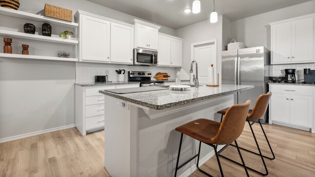 A modern kitchen with white cabinetry, a central island with bar stools, stainless steel appliances, and pendant lighting. - Conveniently Located 3BR Located in West Lubbock (Lubbock)