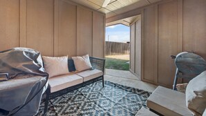 A covered patio area with a sofa, a patterned rug, and a ceiling fan. - Conveniently Located 3BR Located in West Lubbock (Lubbock)