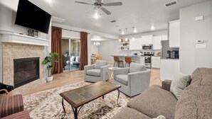 A modern living room with a fireplace, a flat-screen TV, and a ceiling fan. - Conveniently Located 3BR Located in West Lubbock (Lubbock)