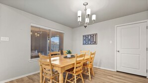 A dining area with a wooden table and chairs, a chandelier, a window with blinds, and a door. - Conveniently Located 3BR Located in West Lubbock (Lubbock)