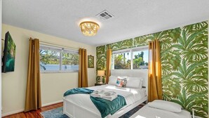 Ein Hotelzimmer mit Bett, Nachttisch, Lampe und Blick ins Freie.