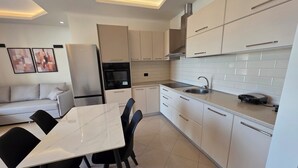 A modern kitchen with white cabinets, a built-in oven, and a sink. - Thomas K Veranda Apartment (Vlorë)