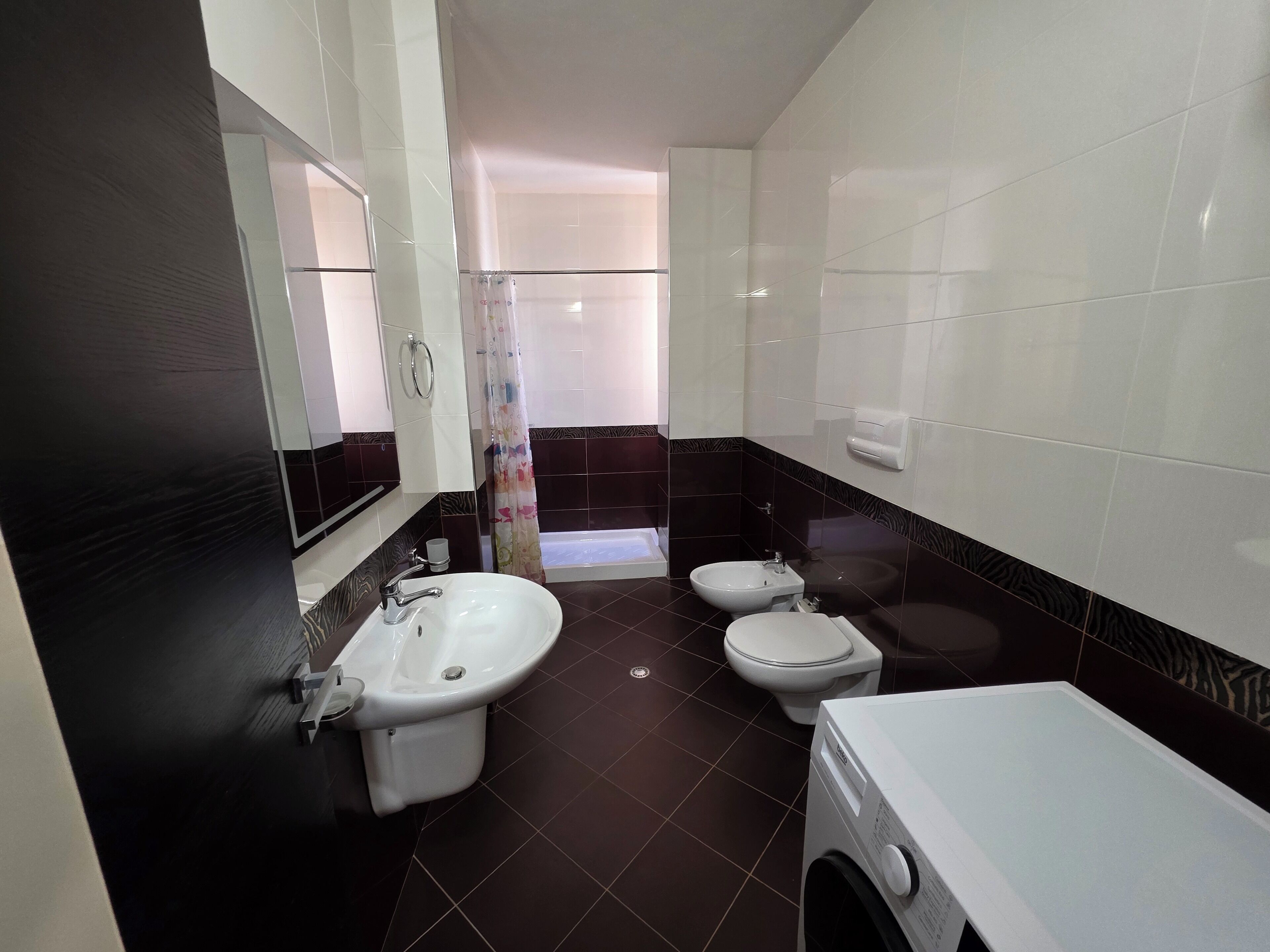 A modern bathroom with a sink, toilet, and washing machine.