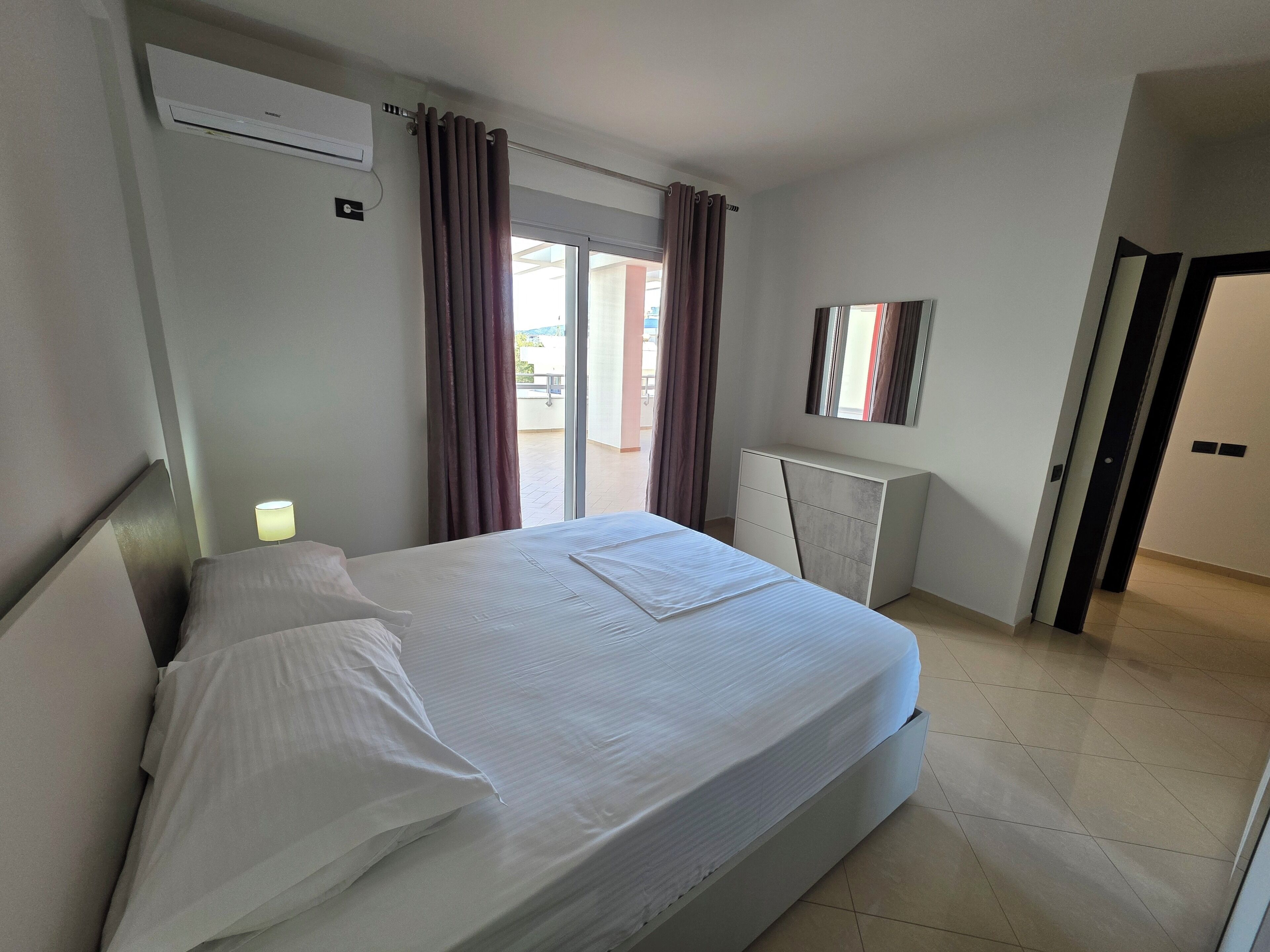 Ein Hotelzimmer mit Bett, Schreibtisch, Klimaanlage und einer Glastür zum Balkon.