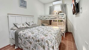 Un dormitorio con literas, una cama individual, un televisor y una ventana con cortinas.