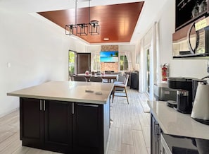 A modern kitchen with a large island, a dining area with a view, and a living space with a fireplace. - Cielo y Mar (Gibson bight)