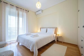 A neatly arranged bedroom with a bed, bedside tables, and a hanging light fixture. - Sunlit Terrace 3BR Apartment – Tavros by ΜΡS (Tavros)