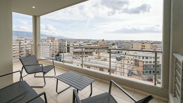 A balcony with a view of a cityscape, featuring a table and chairs. - Sunlit Terrace 3BR Apartment – Tavros by ΜΡS (Tavros)