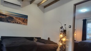 A modern bedroom with a bed, a decorative pinecone vase, and a painting of a beach scene.
