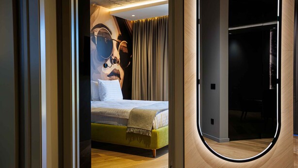 A modern hotel room with a bed, a large mirror, and a wooden floor. - D'otel 47 (Cluj-Napoca)