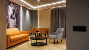 A modern living room with a sofa, chairs, a table, and a large abstract wall mural. - D'otel 47 (Cluj-Napoca)