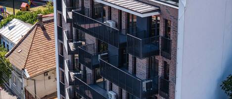 Un immeuble à plusieurs étages doté d’une architecture moderne, avec des balcons et une terrasse sur le toit.