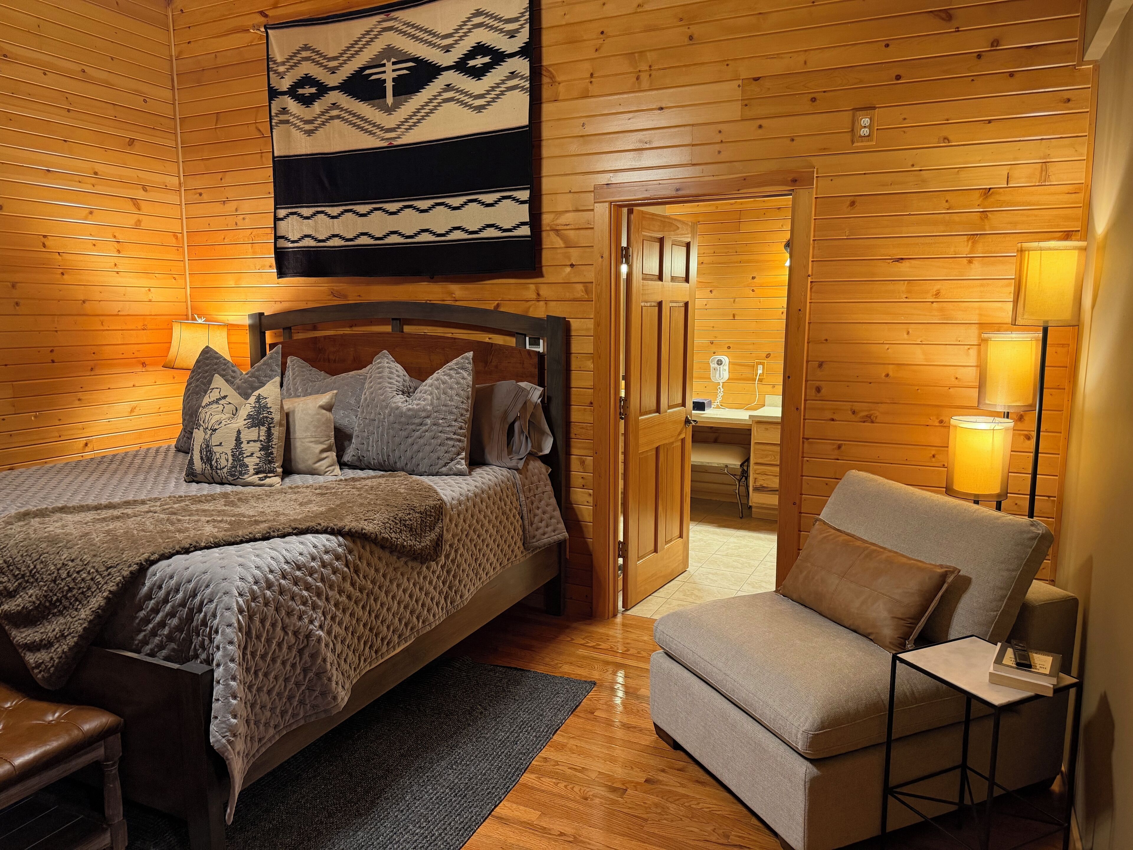 Acogedor dormitorio tipo cabaña de madera con cama, una silla y un escritorio.