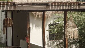 Un espace extérieur abrité, doté de bancs en bois et d’une structure de toit en chaume.