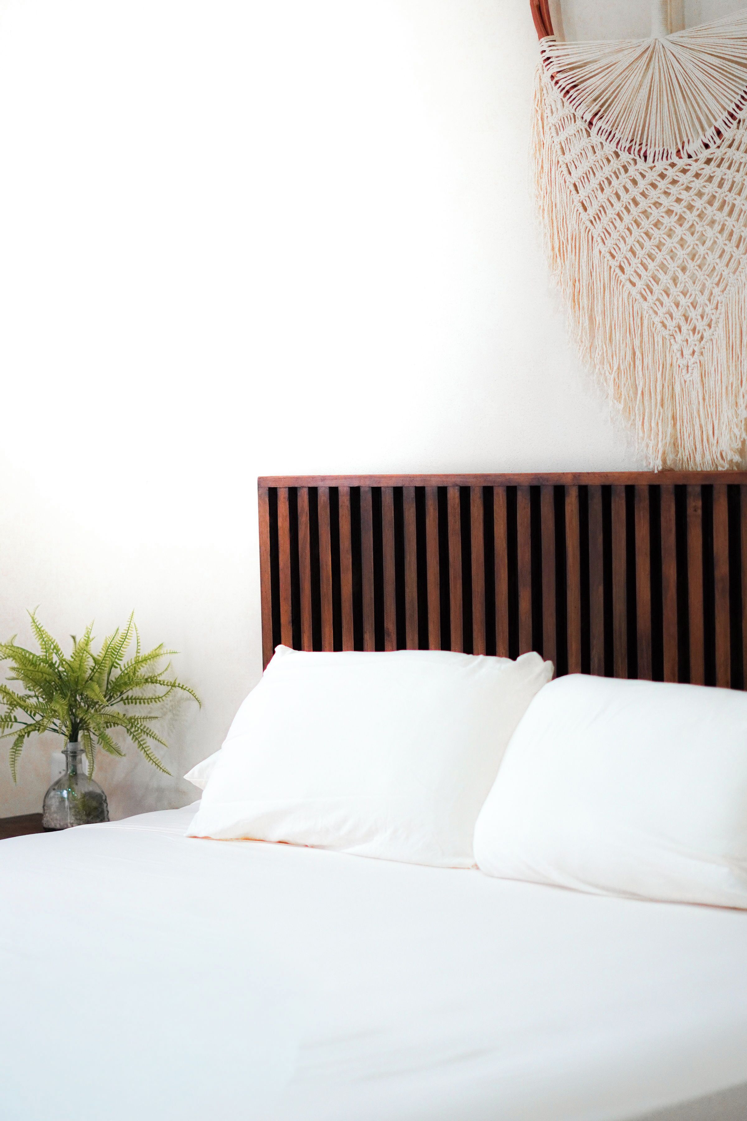 Una cama bien hecha con ropa de cama blanca y un cabecero de madera.