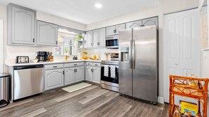 Una cocina moderna con armarios grises, electrodomésticos de acero inoxidable y suelo de madera.
