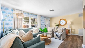Una sala de estar moderna con un sofá, sillones, una mesita de centro y una lámpara.