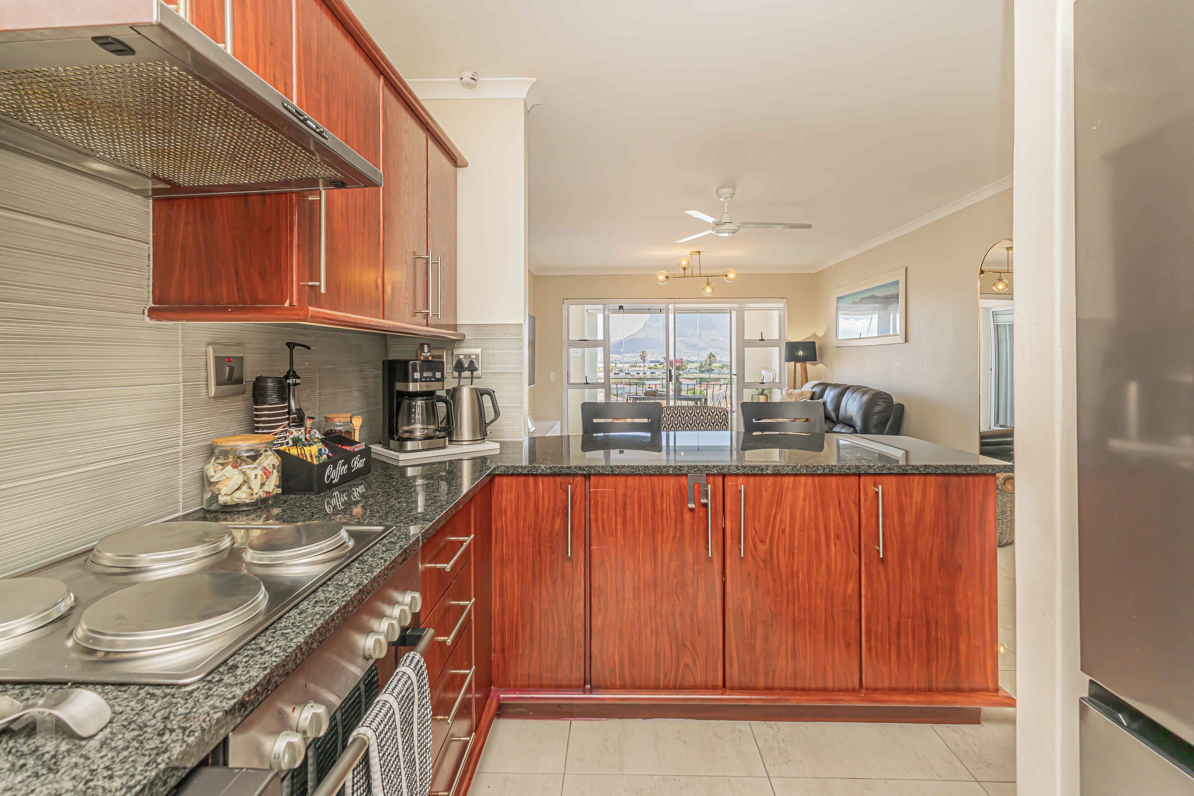 A modern kitchen with wooden cabinets, granite countertops, and stainless steel appliances.
