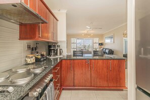 A modern kitchen with wooden cabinets, granite countertops, and stainless steel appliances. - Bella View of Table Mountain to make your stay even more magical (Cape Town)