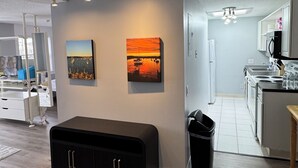 Een moderne woonkamer met een houten vloer, een zwarte tv-kast en twee schilderijen aan de muur.