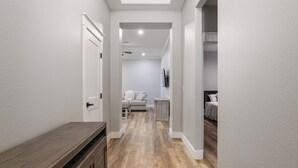 Ein Flur mit einer hölzernen Bank, einer Couch und einem Bett in einem Zimmer mit weißen Wänden und Holzboden.