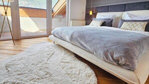 Een slaapkamer met een bed, een groot raam en uitzicht op bergen.