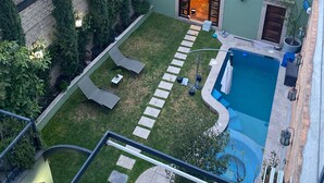 Une piscine sur le toit, agrémentée d’un petit jardin, d’un sentier en pierre et offrant une vue sur le paysage urbain.