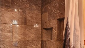 Ein Badezimmer mit dunklen Marmorfliesen, einer Holzbalkendecke und einer Duschvorhang.