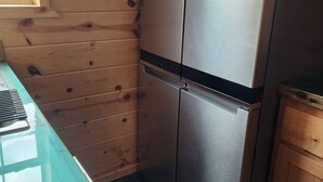 Eine Küche mit Holzwänden, einem Edelstahlkühlschrank und einem schwarzen Fliesenboden.