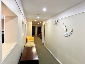 A hallway with a bench, a yellow chair, and a wall-mounted light fixture. - Grand Havre – Perfect for Large Gatherings (Pohénégamook)