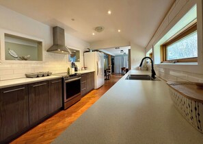 A modern kitchen with a central island, stainless steel appliances, and a view of the dining area.