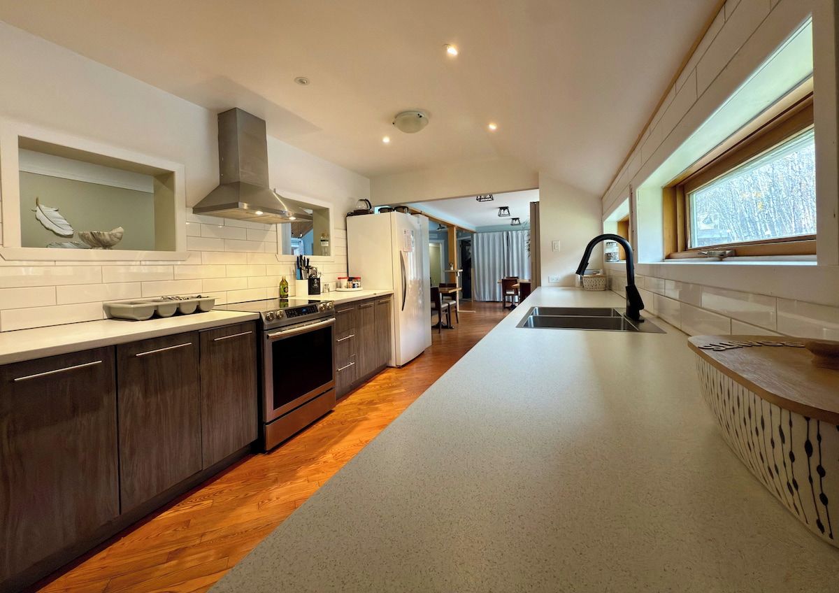 A modern kitchen with a central island, stainless steel appliances, and a view of the dining area.