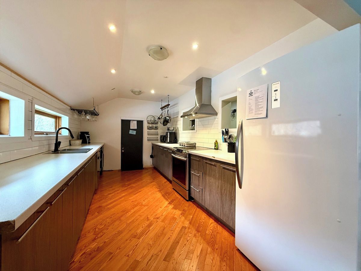 Une cuisine moderne avec un plancher en bois, des appareils en acier inoxydable et un grand îlot central.