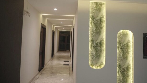 Um corredor moderno com piso de mármore, iluminação embutida e painéis decorativos nas paredes.